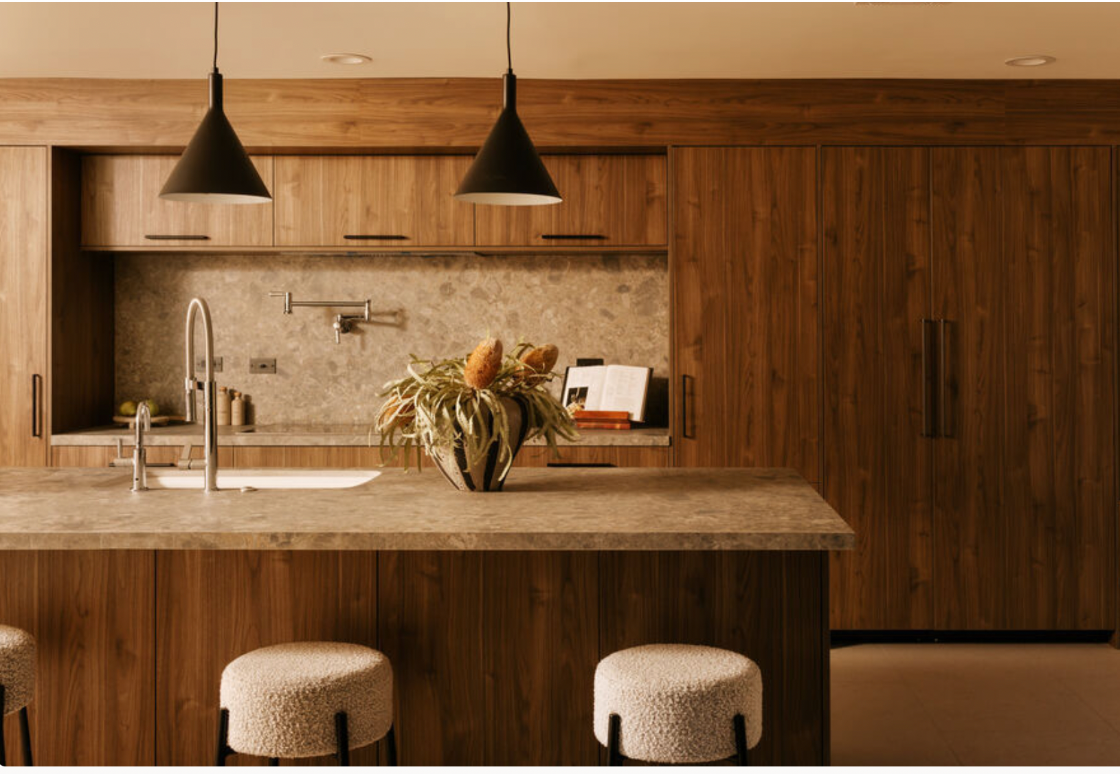 Walnut kitchen with a stone island and pendant lights at Venus Drive